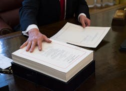 FILE -- President Donald Trump signs the tax reform bill in the Oval Office of the White House in Washington, Dec. 22, 2017. Support for the law &#xf3