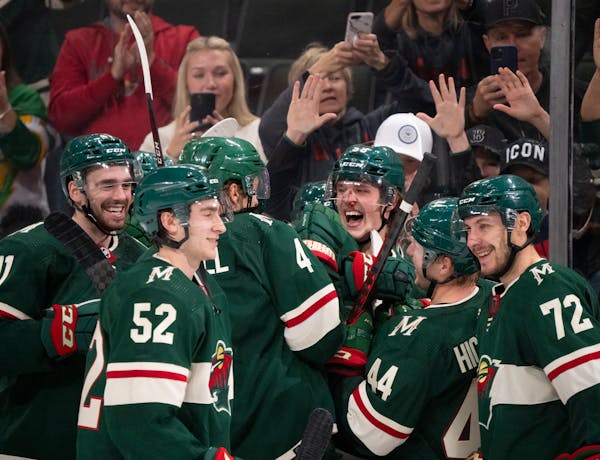 A bloodied Minnesota Wild center Adam Beckman (53) celebrated his game-winning overtime goal with teammates.