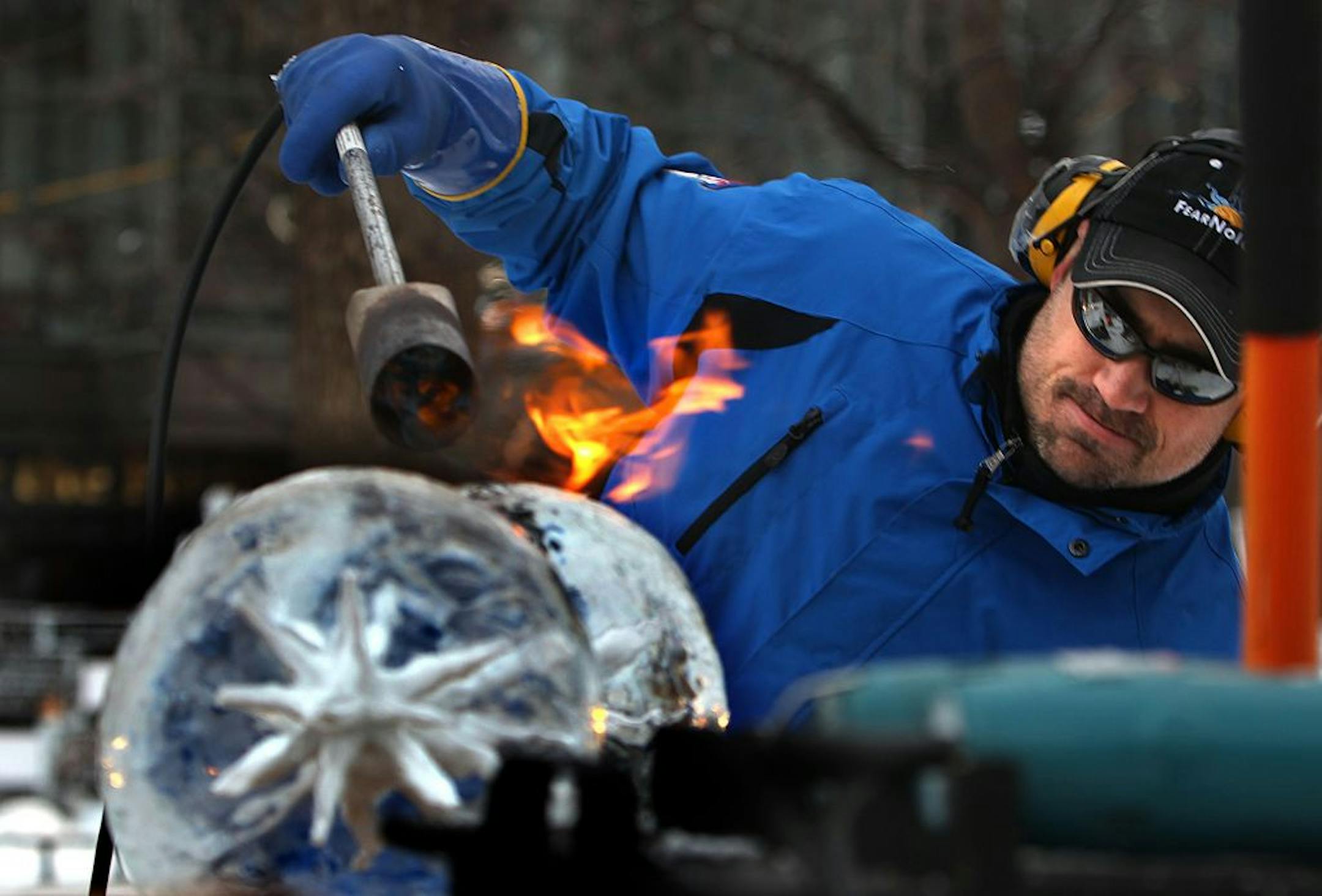 Chris Swarbrick, Hudson, used flames from a blow torch to smooth ice globes that will be used as part of his team's sculpture entitled "Guardians of Enchantment."