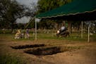 A groundskeeper at Hillcrest Memorial Cemetery mows the lawn near two freshly dug graves on the day of the funeral for Irma Garcia, who was killed dur