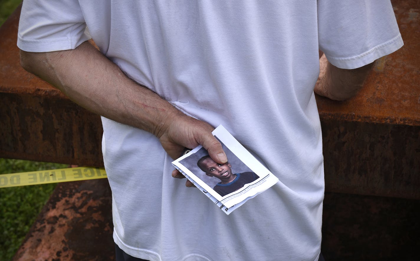 A bystander holds a poster for missing 6-year-old Hamza Elmi near where the boy's scooter was found on the Mississippi River Friday, July 24, 2015, in St. Cloud, Minn. The boy's body was later found in the river. (Dave Schwarz /St. Cloud Times via AP) NO SALES; MANDATORY CREDIT ORG XMIT: MIN2015072414292948