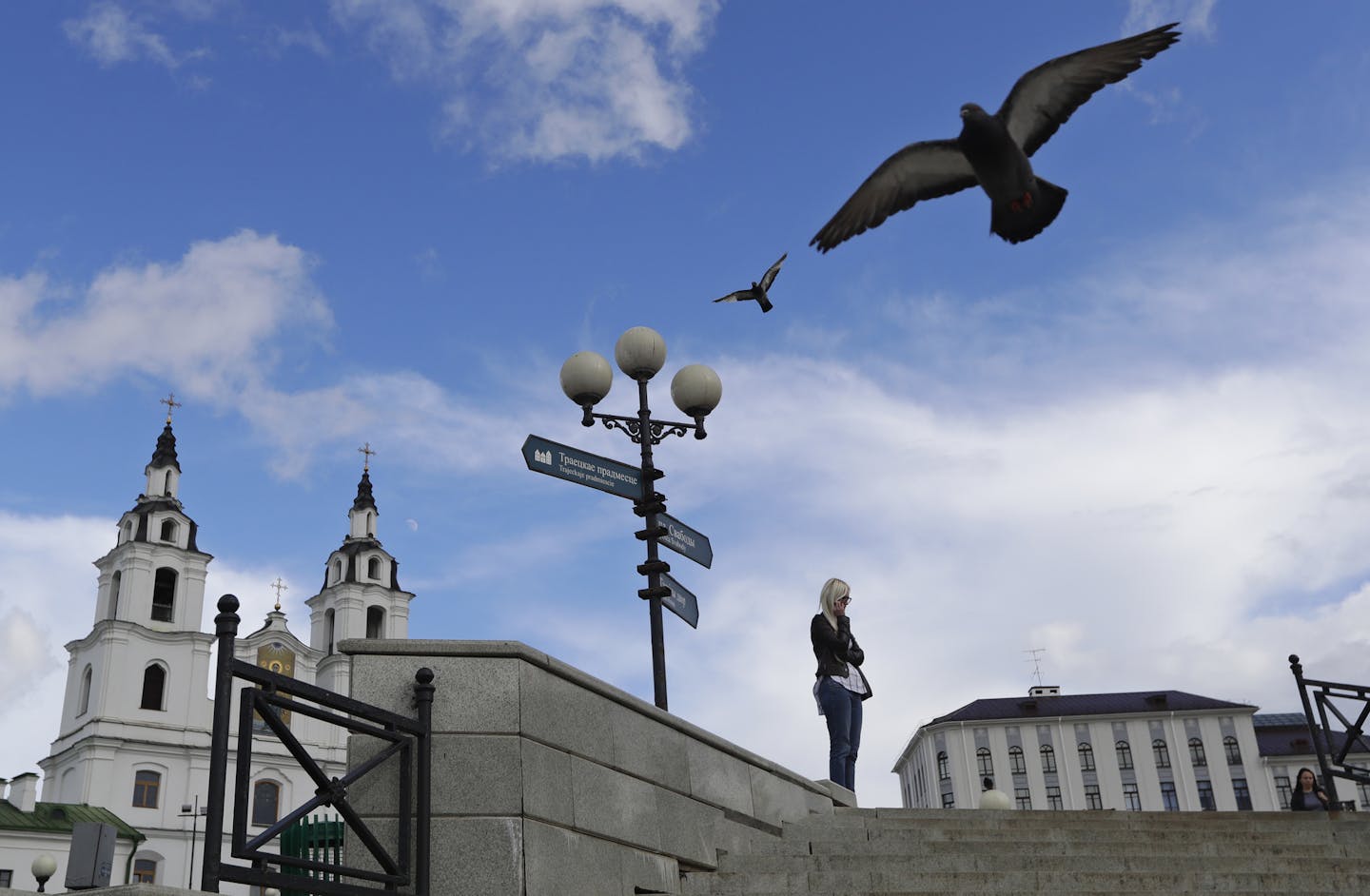 A woman speaks on her cellphone with an Orthodox Cathedral church on the background on a sunny day in Minsk, Belarus, Wednesday, July 10, 2019. (AP Photo/Sergei Grits) ORG XMIT: MIN104