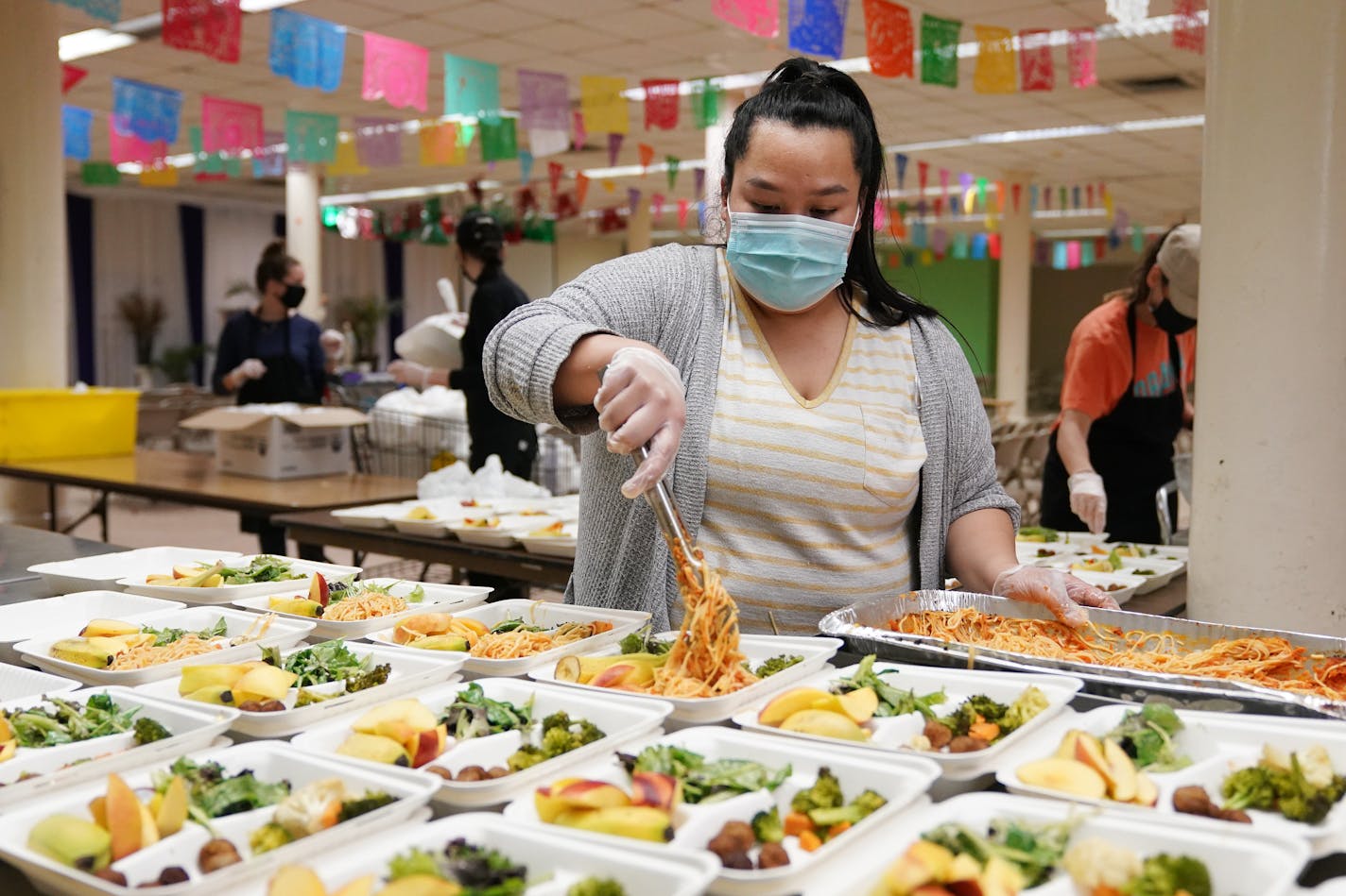 Kao Yong Yang dished out spaghetti into portioned meals to be distributed to those in need Tuesday evening at Holy Rosary Catholic Church. ] ANTHONY SOUFFLE • anthony.souffle@startribune.com