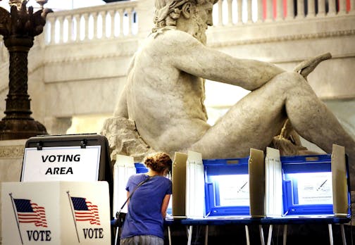 With the Father of Waters sculpture looming to her rear, Kym Spotts of Minneapolis completes her absentee ballot at the Minneapolis City Hall Friday, Aug. 8, 2014, in Minneapolis, MN. Spotts, who said she will be out of town on Tuesday, said she requested the absentee ballot form but received the wrong form in the mail and it turned into a "wild goose chase."] (DAVID JOLES/STARTRIBUNE) djoles@startribune A heated primaries have drawn an outpouring of absentee ballots in the first race where vote