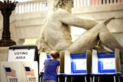 With the Father of Waters sculpture looming to her rear, Kym Spotts of Minneapolis completes her absentee ballot at the Minneapolis City Hall Friday, 