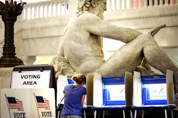 With the Father of Waters sculpture looming to her rear, Kym Spotts of Minneapolis completes her absentee ballot at the Minneapolis City Hall Friday, 