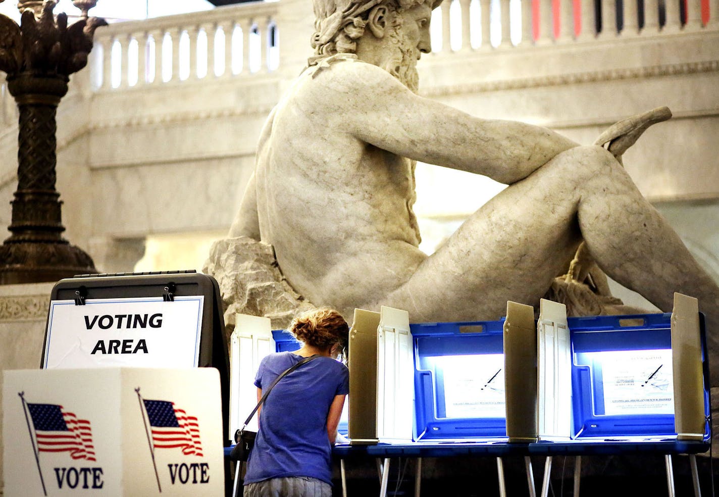 With the Father of Waters sculpture looming to her rear, Kym Spotts of Minneapolis completes her absentee ballot at the Minneapolis City Hall Friday, Aug. 8, 2014, in Minneapolis, MN. Spotts, who said she will be out of town on Tuesday, said she requested the absentee ballot form but received the wrong form in the mail and it turned into a "wild goose chase."] (DAVID JOLES/STARTRIBUNE) djoles@startribune A heated primaries have drawn an outpouring of absentee ballots in the first race where vote