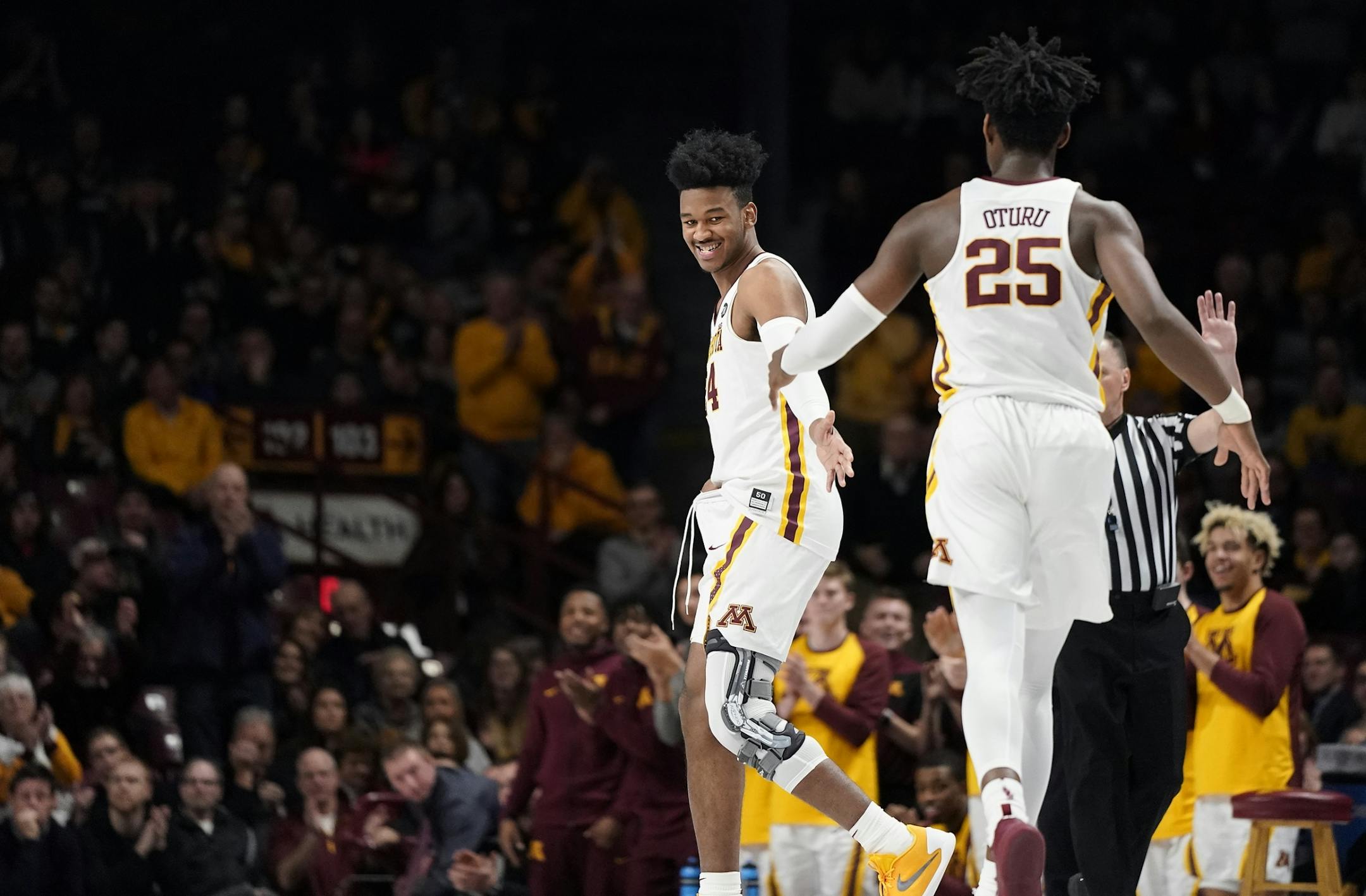 Minnesota forward Eric Curry (24) gets a welcome from Minnesota center Daniel Oturu (25) after coming into the game for the first time during the first half.