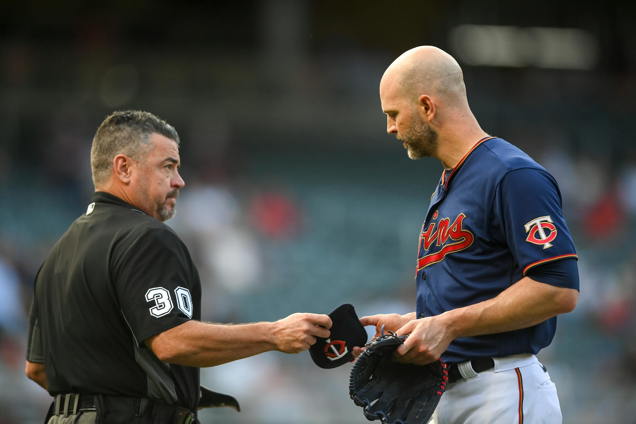 MLB Umpire Rob Drake (30) checked the hat and gloves of Minnesota Twins starting pitcher J.A. Happ (33) for banned substances after the top of the first inning.