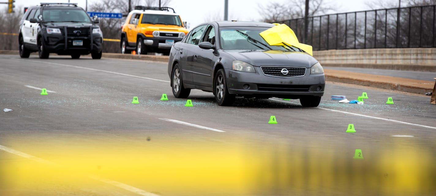 Members of the crime lab collected evidence from around the car where one man was shot to death and another wounded on 7th St. N heading into downtown Sunday in Minneapolis.