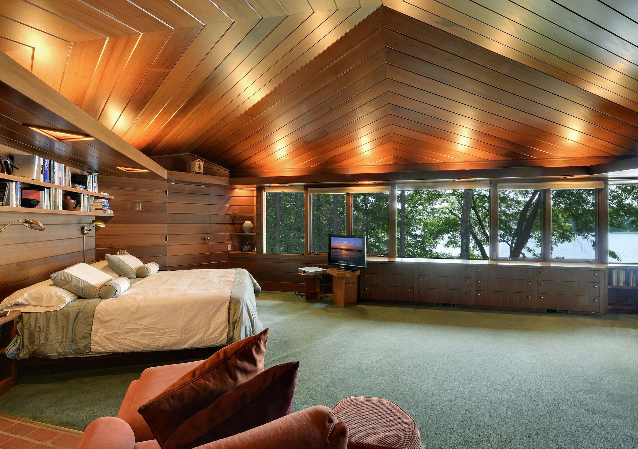 The master suite has a pitched ceiling, walls of glass, stone floors and its own patio.