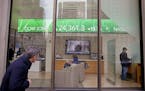 FILE- In this Feb. 6, 2018, file photo, a passer-by peers in the window while investors congregate inside at the Fidelity Investments office on Congre