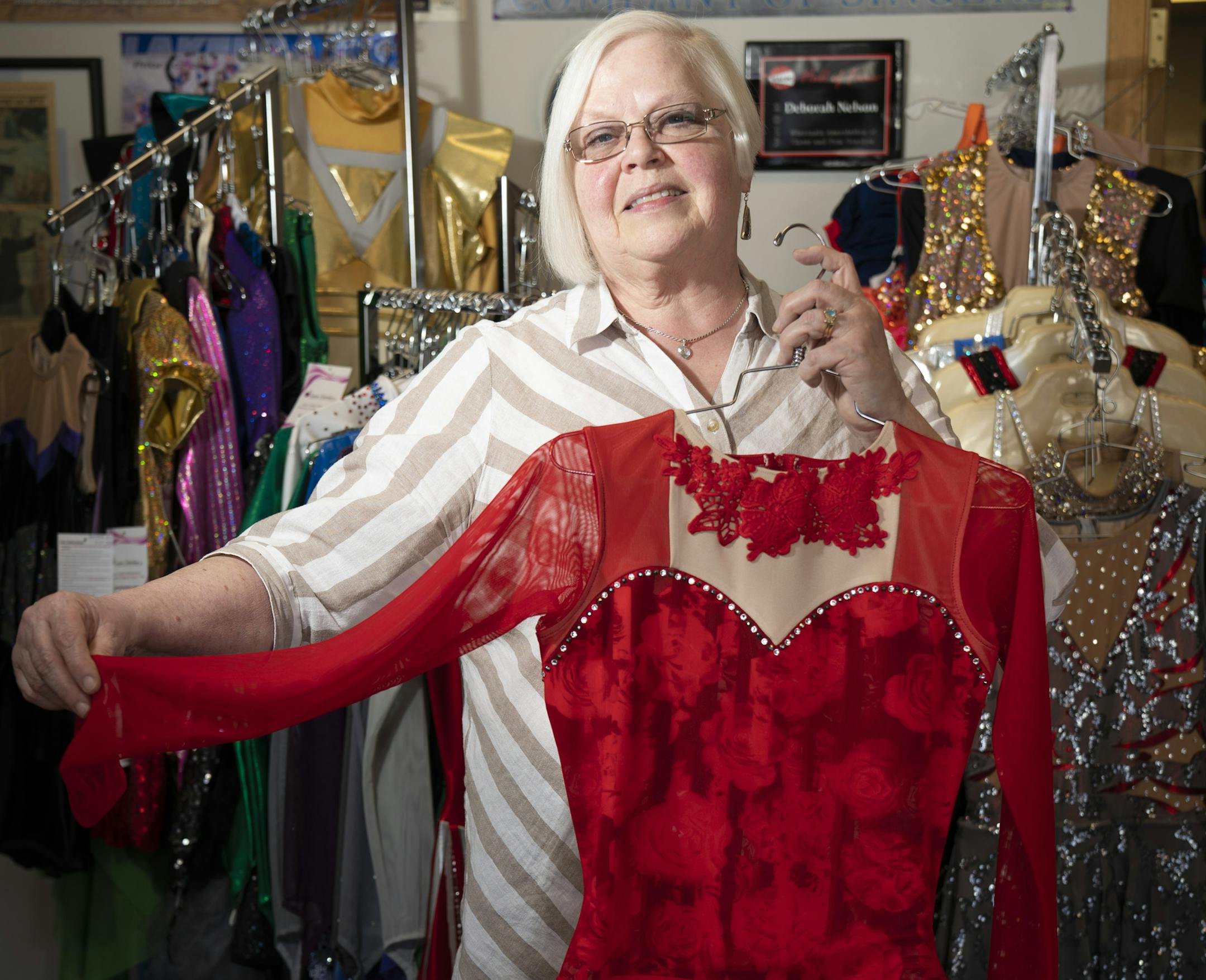 Deborah Nelson, owner of Satin Stitches, posed for a picture holding one of her custom made dance costumes in her store in Coon Rapids.