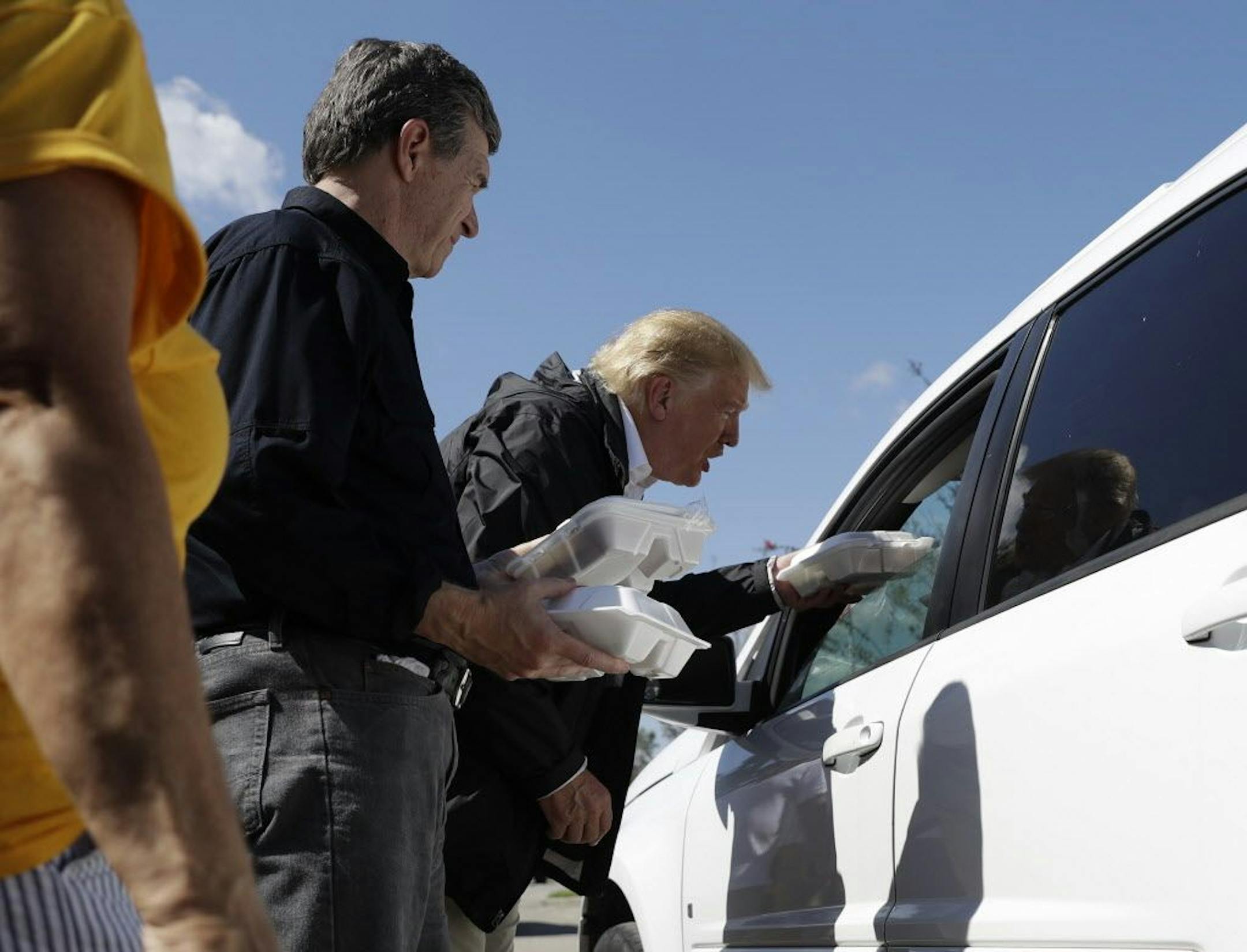 President Donald Trump and North Carolina Gov. Roy Cooper, left, hand out food at Temple Baptist Church, where food and other supplies are being distributed during Hurricane Florence recovery efforts, Wednesday, Sept. 19, 2018, in New Bern, N.C.