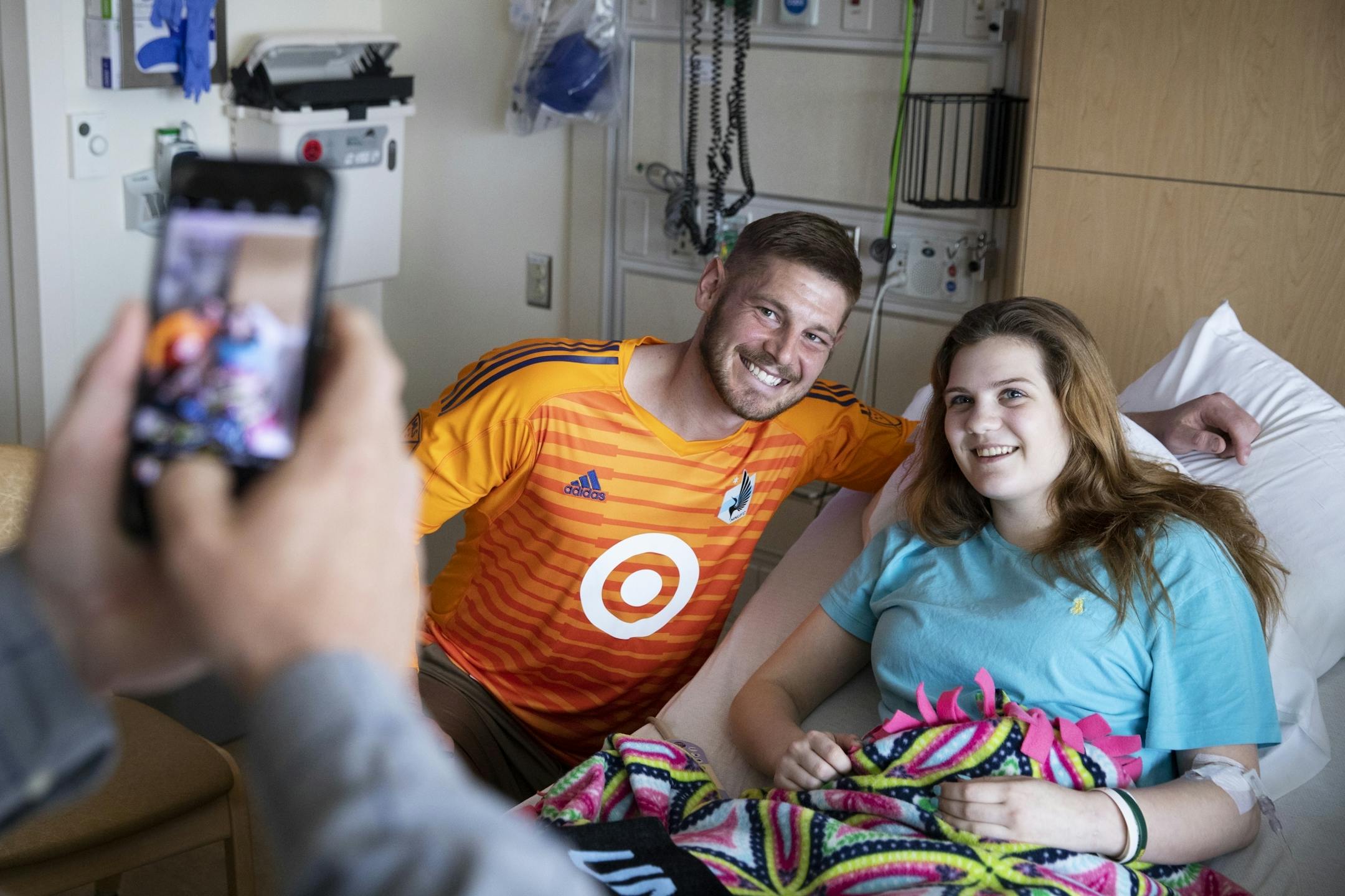 Abbey Eichelberger, 17, who is in the hospital with a swelled gallbladder, poses for a photo with Minnesota United goalkeeper Matt Lampson during his visit to the hospital.