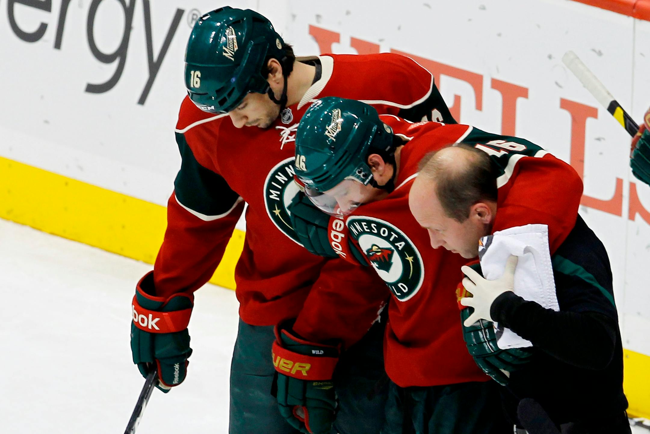 Minnesota Wild defenseman Jared Spurgeon, center, is helped off the ice by trainer Don Fuller, right, and right wing Brad Staubitz (16) during the first period of an NHL hockey game against the Colorado Avalanche in St. Paul, Minn., Monday, Dec. 26, 2011. Spurgeon was injured by a check from behind by Colorado Avalanche left wing Cody McLeod (55). (AP Photo/Ann Heisenfelt)