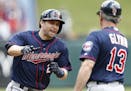 Minnesota Twins' Brian Dozier, left, is congratulated by third base coach Gene Glynn (13) on his lead-off home run against the Texas Rangers during th