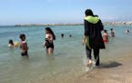 FILE - In this Aug.4 2016 file photo made from video, Nissrine Samali, 20, gets into the sea wearing traditional Islamic dress, in Marseille, southern