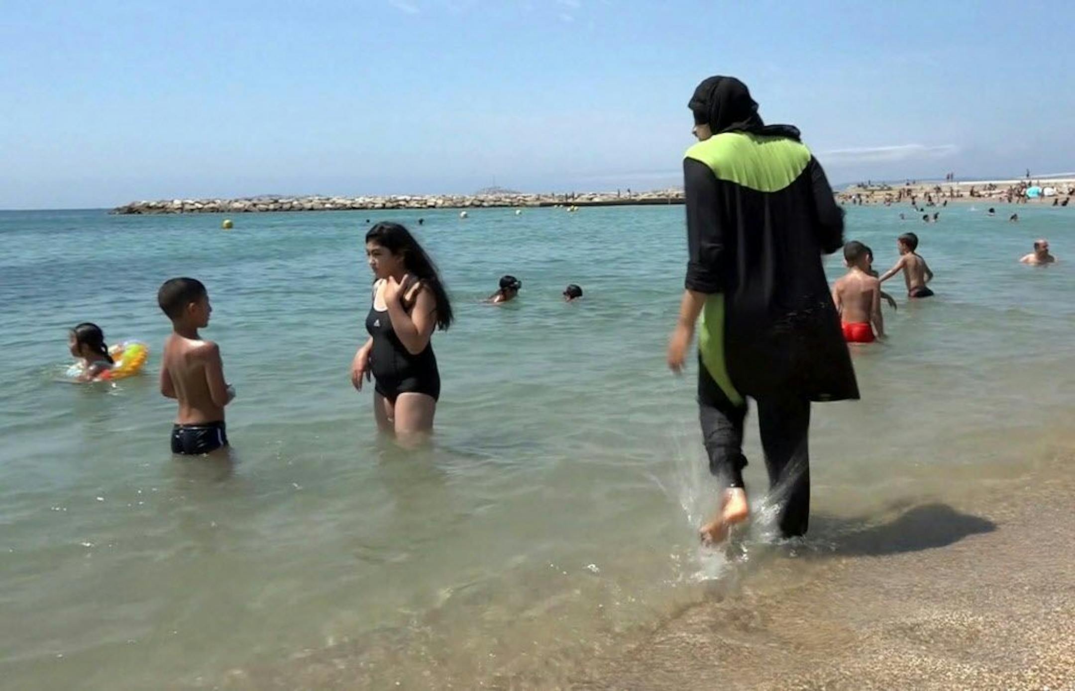 FILE - In this Aug.4 2016 file photo made from video, Nissrine Samali, 20, gets into the sea wearing traditional Islamic dress, in Marseille, southern France. The French resort of Cannes has banned full-body, head-covering swimsuits worn by some Muslim women from its beaches, citing security concerns. A City Hall official said the ordinance, in effect for August, could apply to burkini-style swimsuits.