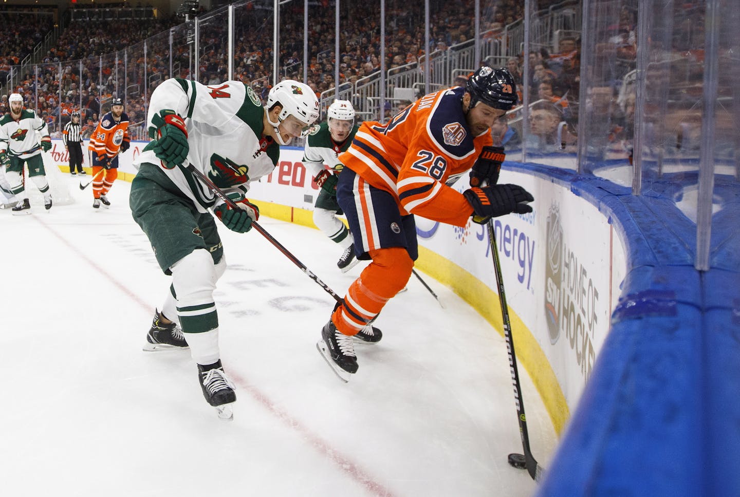 Minnesota Wild' Joel Eriksson Ek (14) and Edmonton Oilers' Kyle Brodziak (28) battle in the corner during second period NHL hockey action in Edmonton, Alberta, on Tuesday, Oct. 30, 2018. (Jason Franson/The Canadian Press via AP)