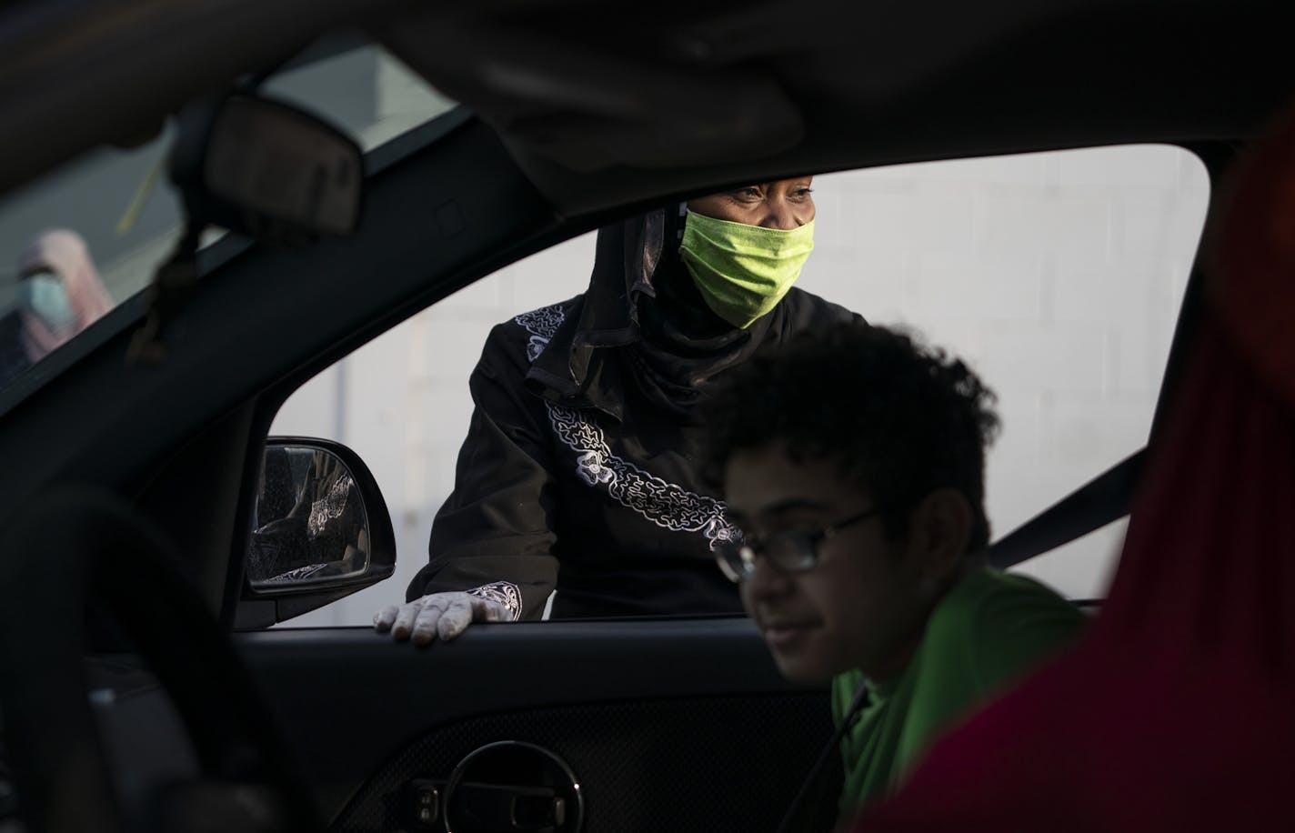 Aminata Keita talked with Ali Tafroukt (in car) and others in the car as she gave them meals in Columbia Heights, Minn., on Thursday, May 7, 2020. She and other volunteers serve from 100 to 150 boxes each night for Muslims breaking their fasts at sundown, and who typically would be going to their mosque for a community meal.