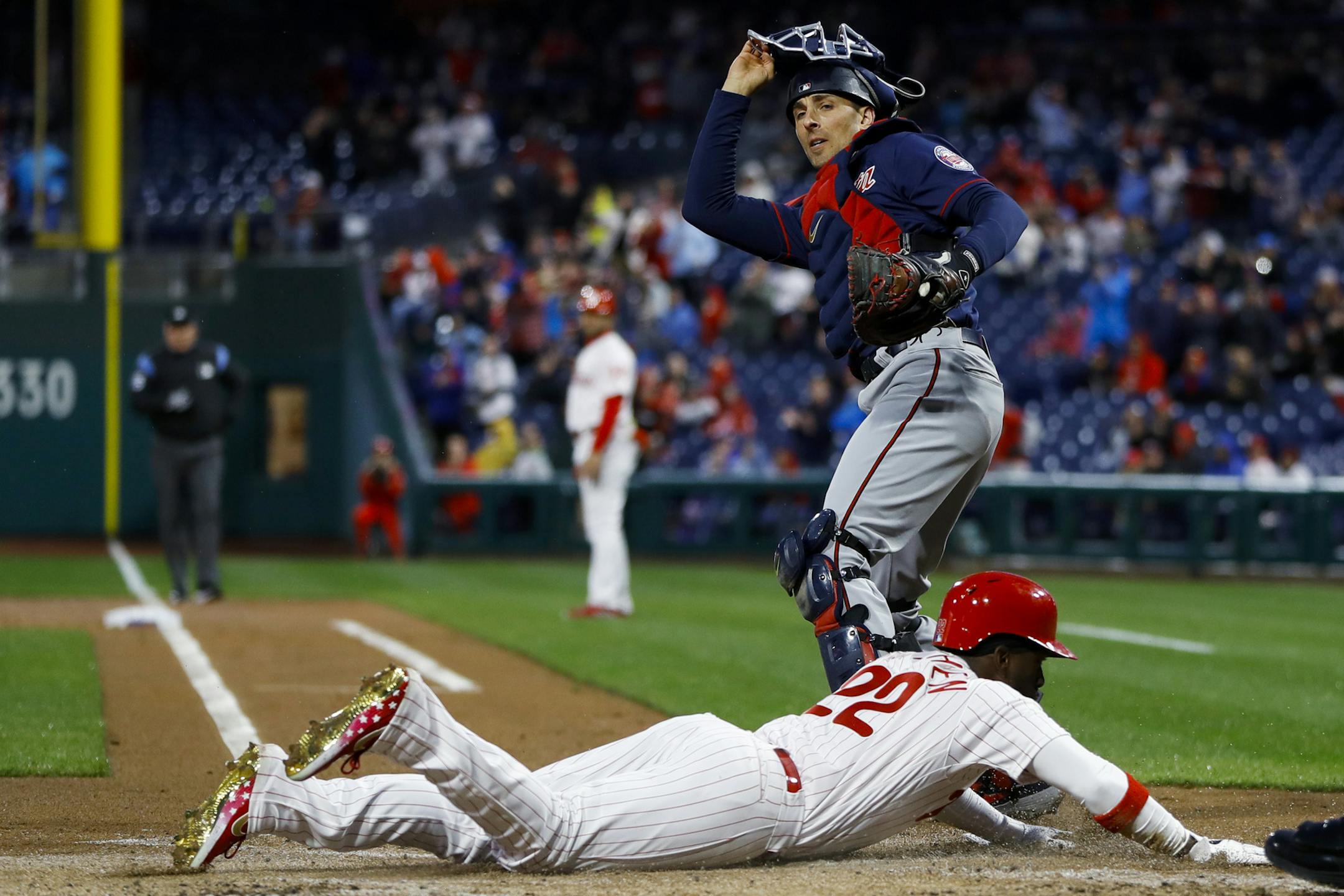 Philadelphia Phillies' Andrew McCutchen, bottom, scores past Minnesota Twins catcher Jason Castro during the first inning of a baseball game Friday, April 5, 2019, in Philadelphia. (AP Photo/Matt Slocum)