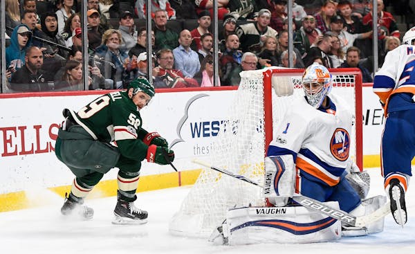 Minnesota Wild right wing Zack Mitchell (59) turned around to see his puck sneak behind the leg padding of New York Islanders goalie Thomas Greiss (1)