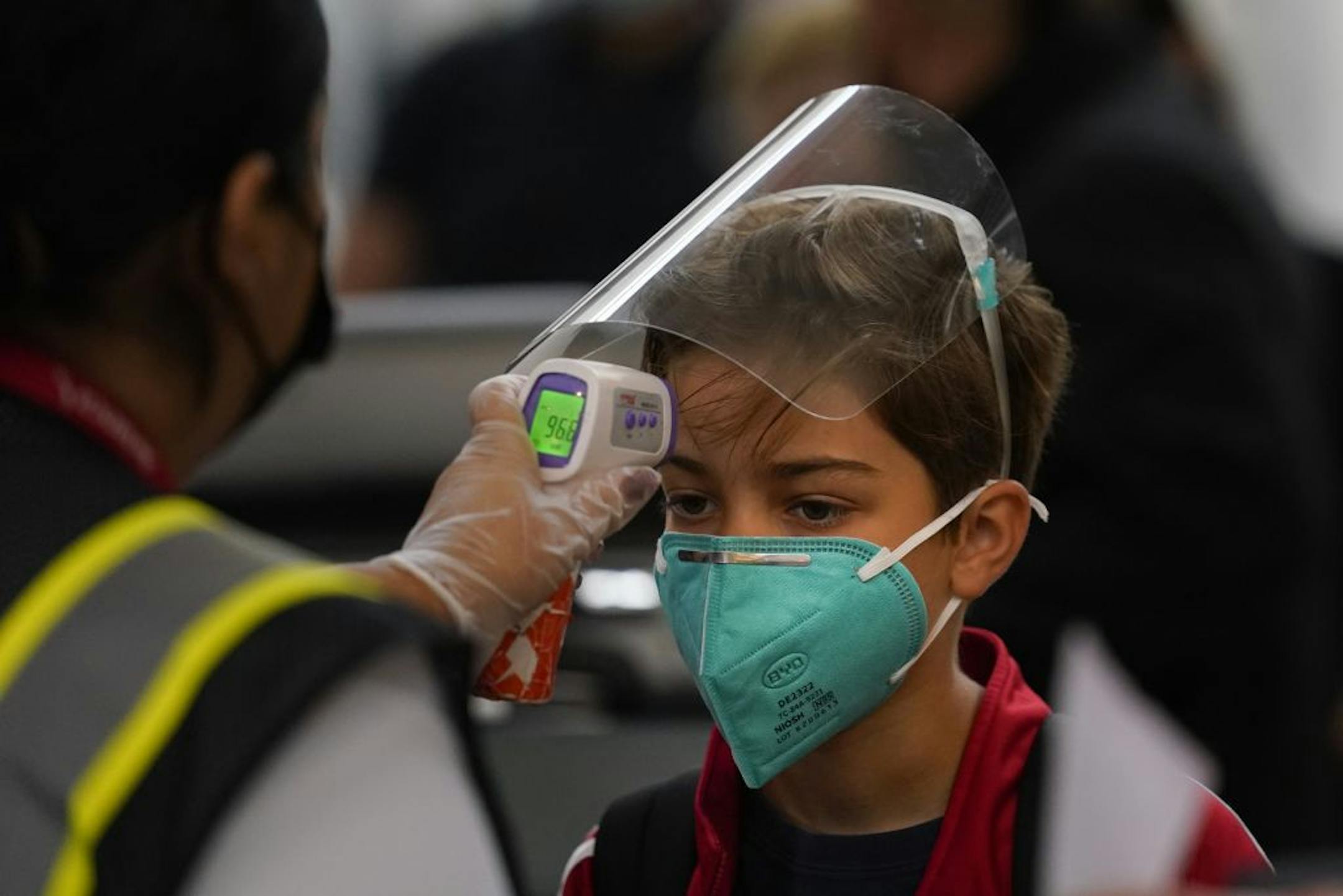 A boy gets his temperature checked while waiting in line to check in at the Los Angeles International Airport in Los Angeles, Monday, Nov. 23, 2020. About 1 million Americans a day packed airports and planes over the weekend even as coronavirus deaths surged across the U.S. and public health experts begged people to stay home and avoid big Thanksgiving gatherings.