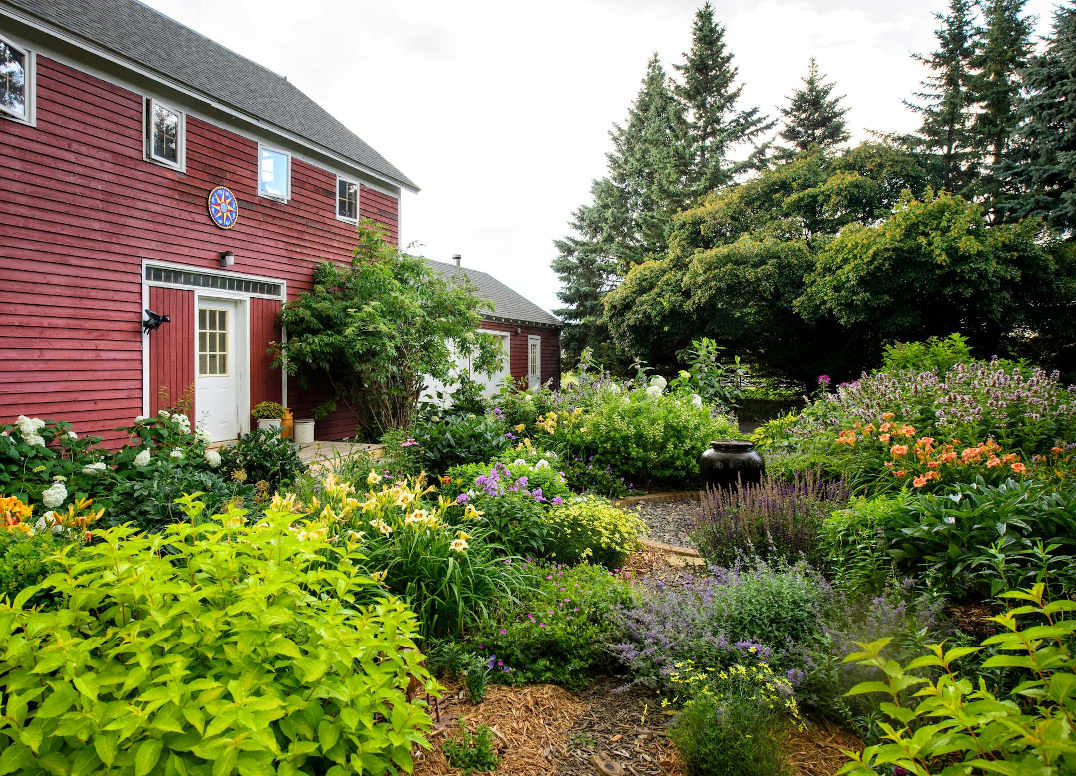 Their ancient granary is a quaint backdrop for one of Moran’s gardens. She designs with an eye to height, color, texture and bloom time.