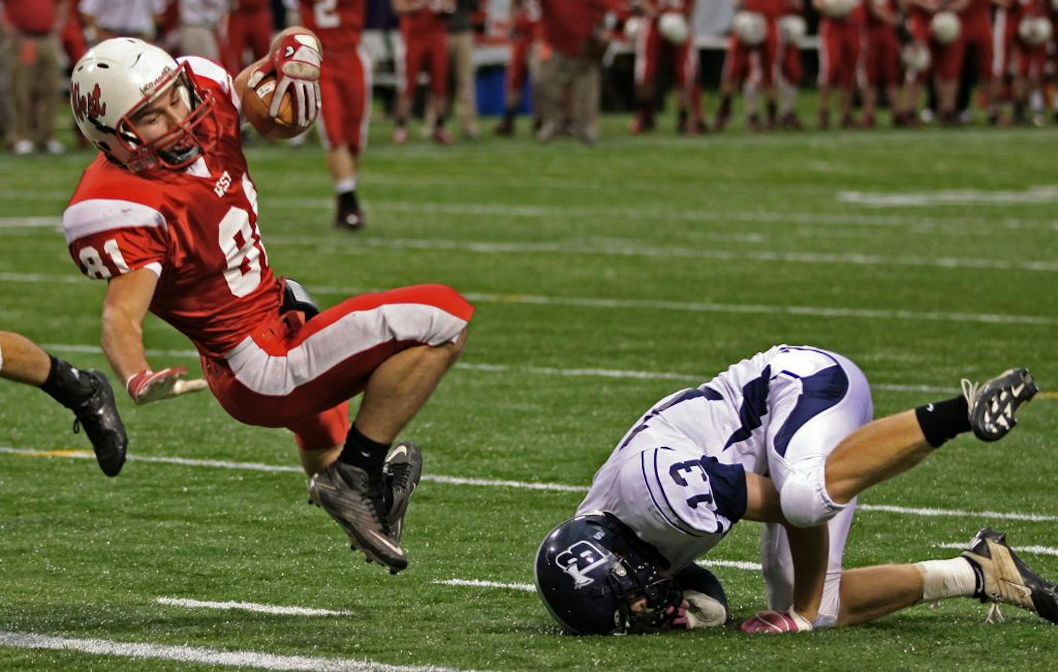 Mankato West vs. Bemidji, Class 3A semi-final game at the Metrodome on 11/18/11. (left to right) Mankato West's Hunter Friesen twisted through the air as he scored a first half touchdown as he was defended by Bemidji's Cody Rutledge.
