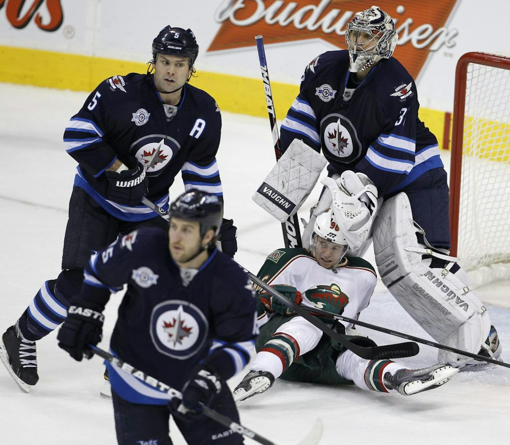 Clockwise from bottom left, Winnipeg Jets' Tanner Glass (15), Mark Stuart (5), goaltender Ondrej Pavelec (31) and Minnesota Wild's Pierre-Marc Bouchard (96) in front of the Jets net during third period NHL hockey action in Winnipeg Tuesday, Dec. 13, 2011.
