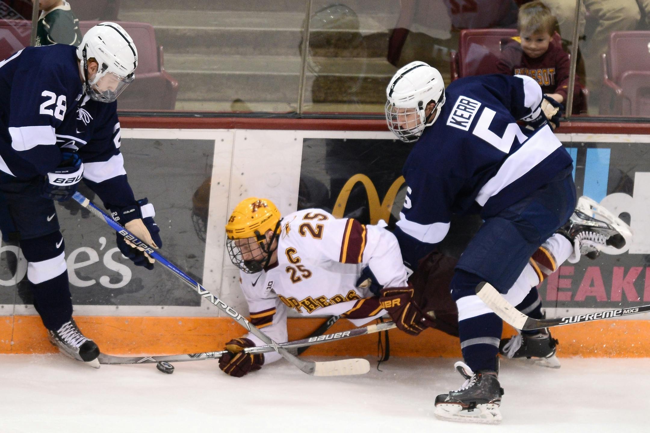 Minnesota Golden Gophers center Justin Kloos (25) fell to the ice while going after the puck being defended by Penn State Nittany Lions forward Alec Marsh (28) and defenseman Kevin Kerr (5) in the first period.