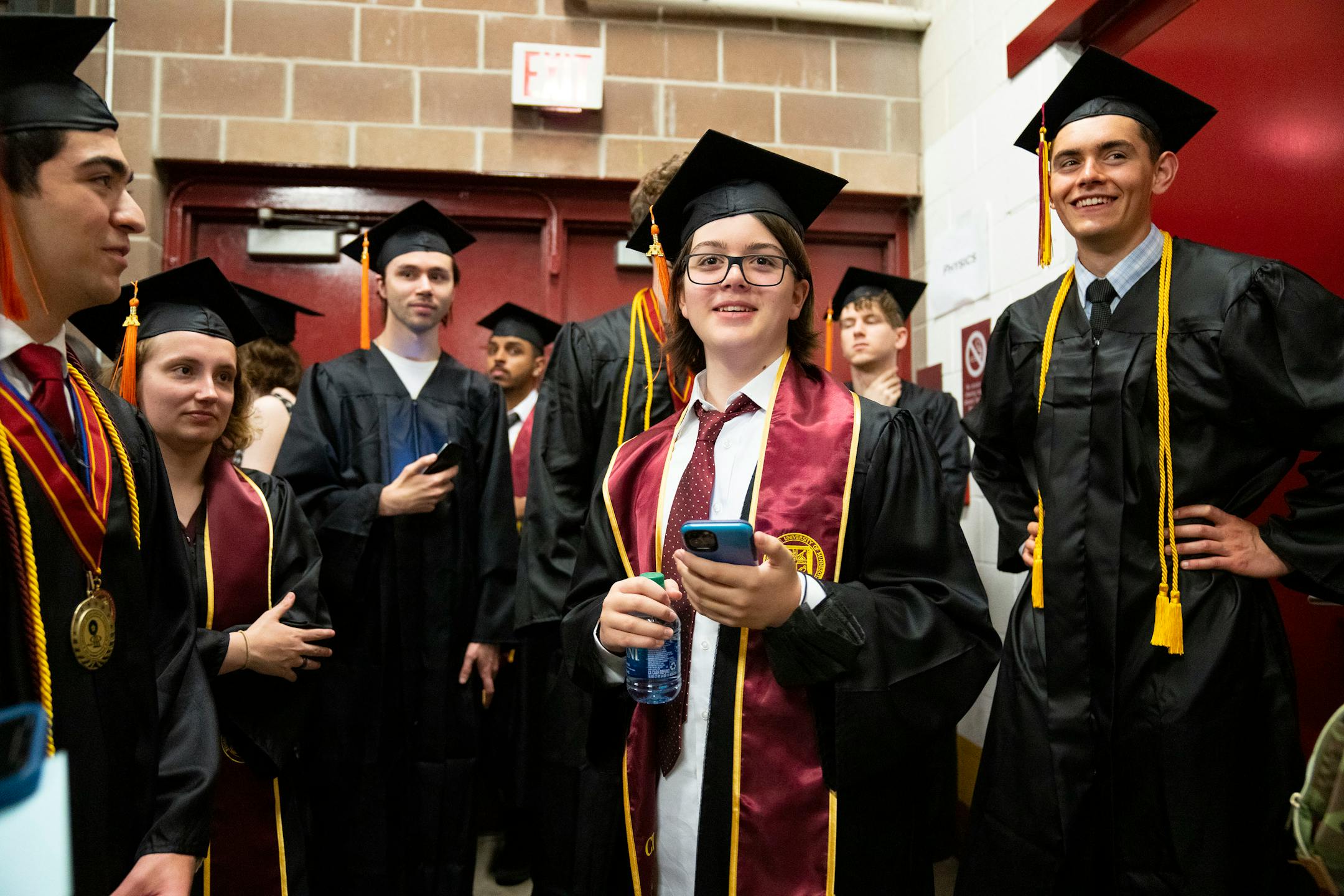 Elliott Tanner, 13, stands among his fellow physics department graduates in a holding area before their graduation.