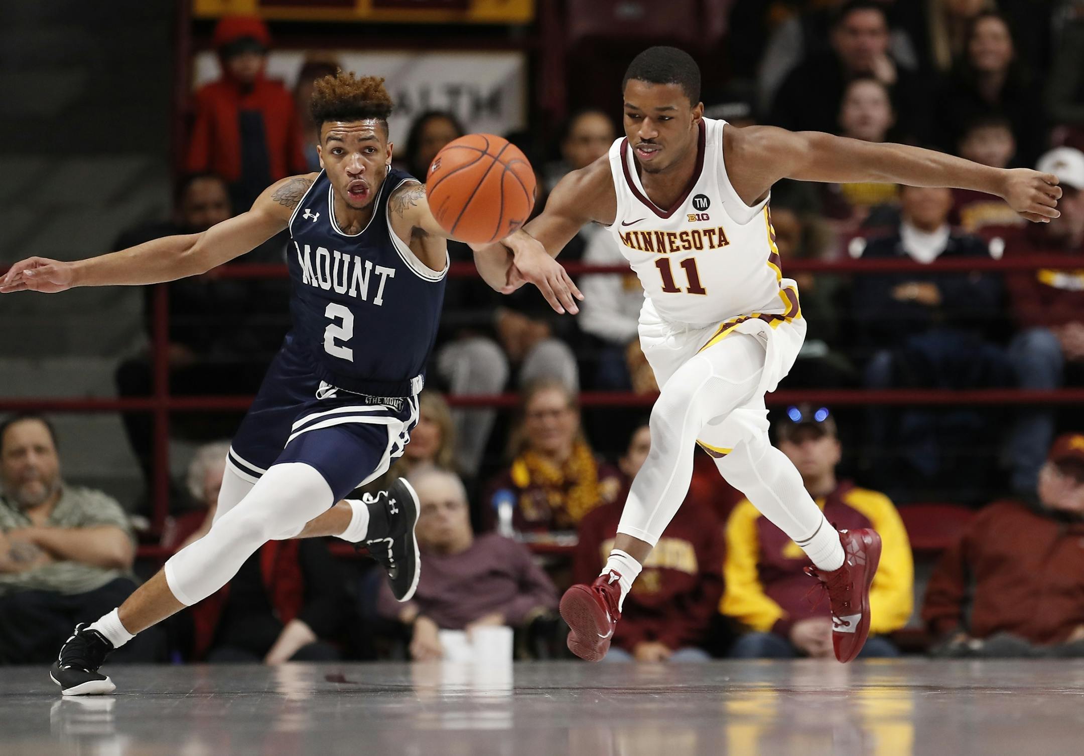Minnesota guard Isaiah Washington (11), right, and Mount St. Mary's guard Dee Barnes (2) chase a loose ball during the first half.