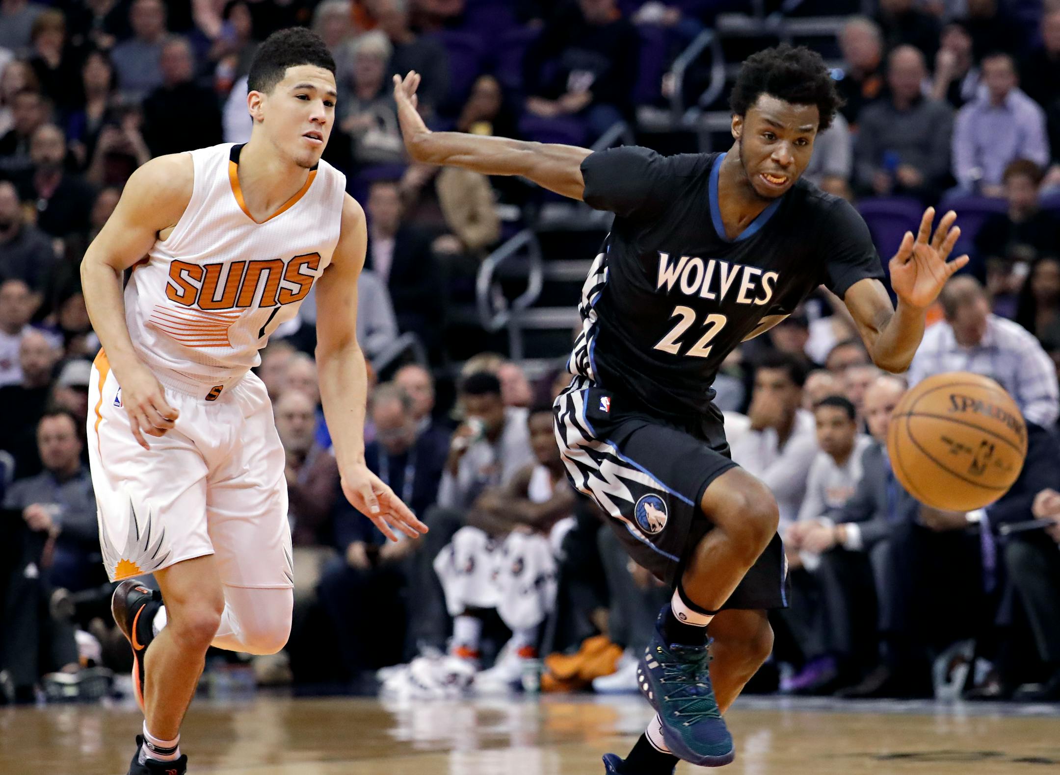 Minnesota Timberwolves forward Andrew Wiggins (22) and Phoenix Suns guard Devin Booker (1) chase down a loose ball during the first half of an NBA basketball game, Tuesday, Jan. 24, 2017, in Phoenix. (AP Photo/Matt York)