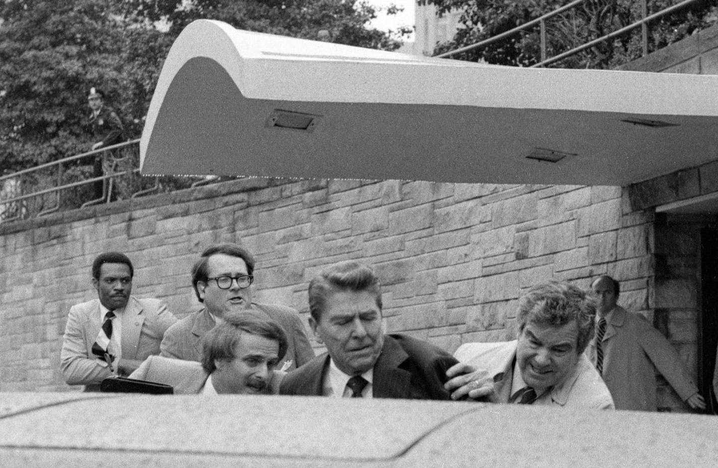 U.S. President Ronald Reagan waves and then looks up before being shoved into the President's limousine by secret service agents after being shot outside a Washington hotel Monday, March 30, 1981. (AP Photo/Ron Edmonds) ORG XMIT: APHS183