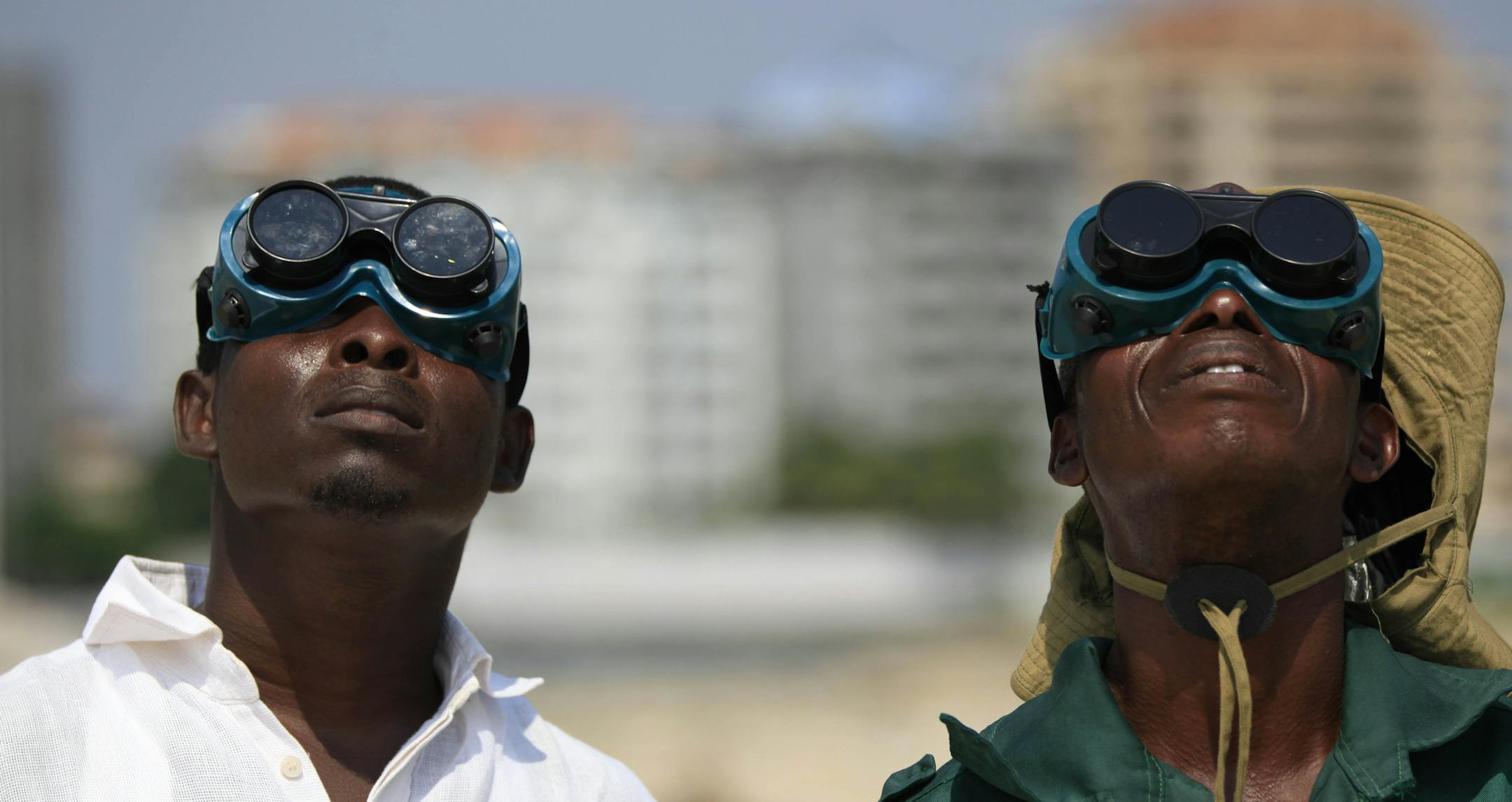 Nigerian men wear welding goggles to watch a partial solar eclipse in Lagos, Nigeria, Sunday, Nov. 3, 2013. Clouds moving over the city allowed only brief views of the eclipse which in southern Europe was partial. The total eclipse was seen sweeping east across Africa. (AP Photo/Sunday Alamba)