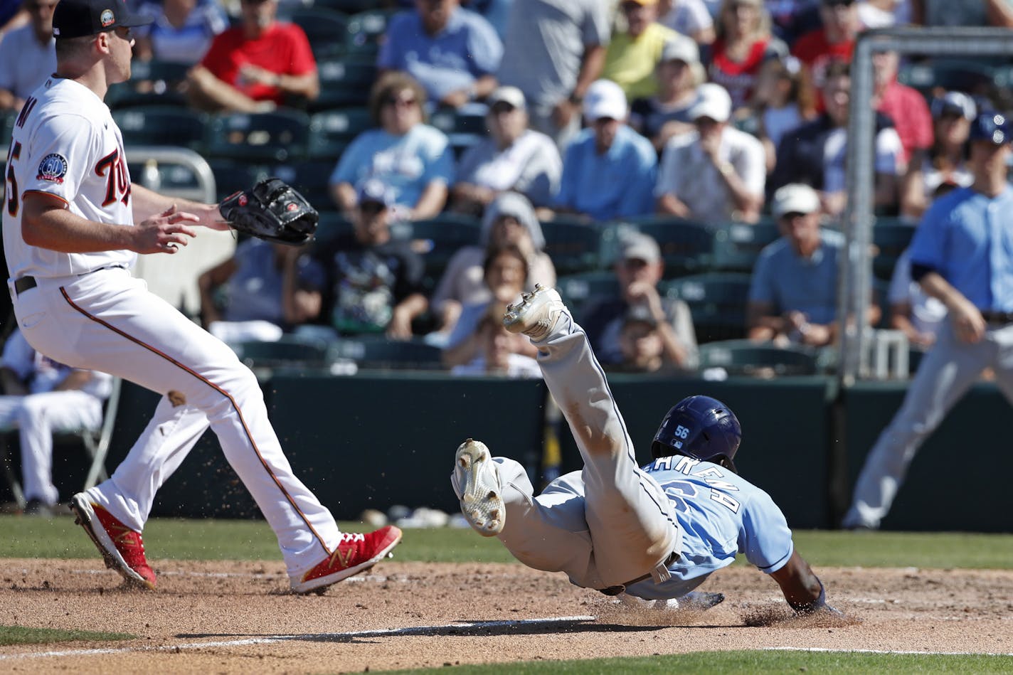 Tampa Bay Rays' Randy Arozarena slides into home plate to score on a passed ball as Minnesota Twins pitcher Trevor May, left, looks for a throw during a spring training baseball game, Friday, March 6, 2020, in Fort Myers, Fla. (AP Photo/Elise Amendola)