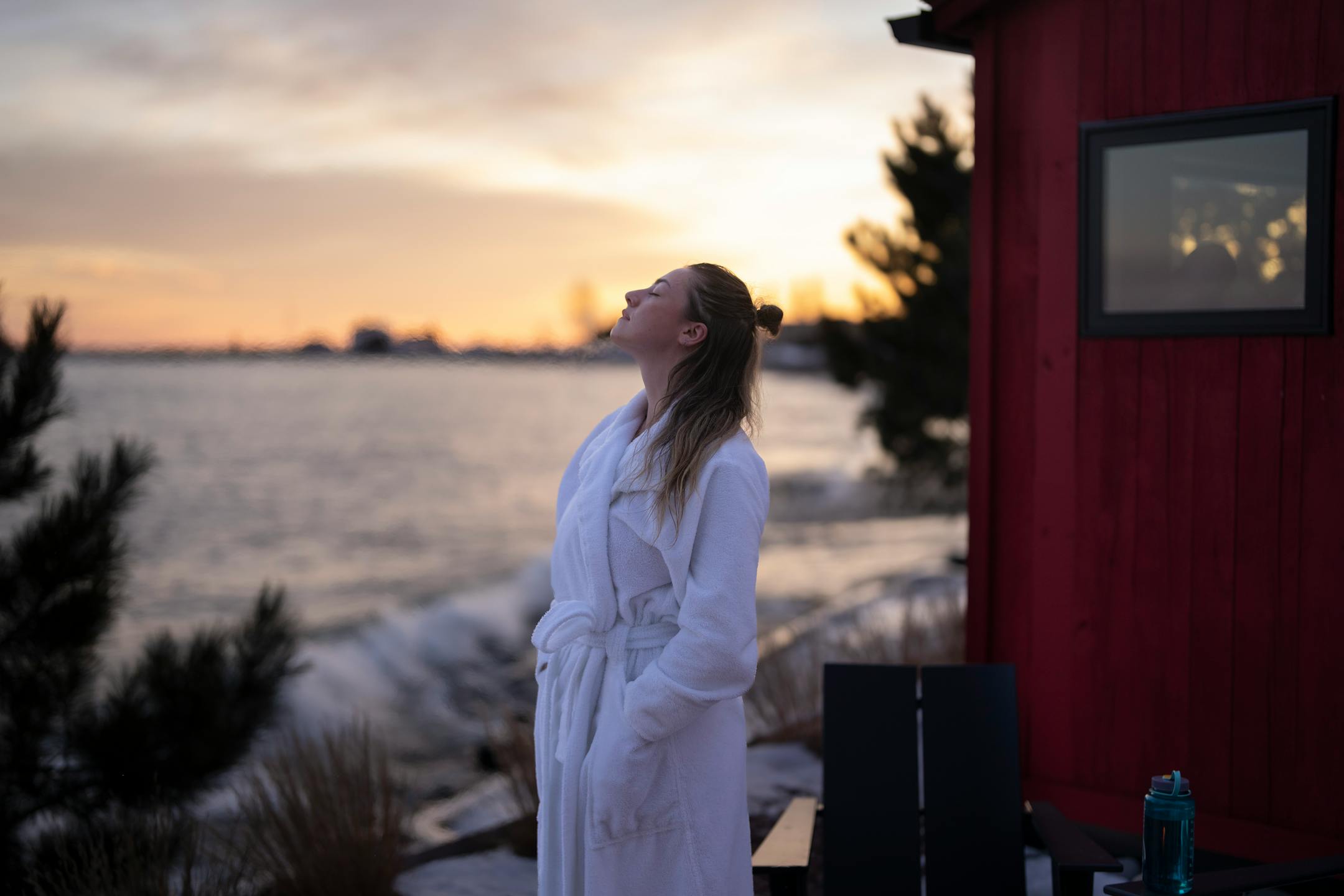 Ana Macy closes her eyes and breathes in cold air while taking a break from a sauna by the fire pit at Sisu and Löyly Sauna.