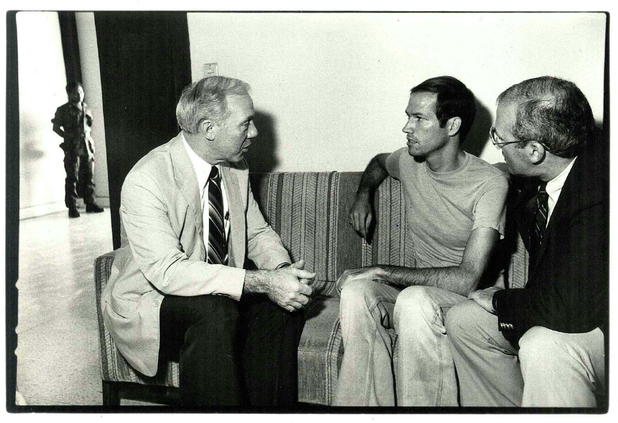 Mn. Representative James Oberstar, left, talks with freelance reporter T.J. Western of the Twin Cities, in police custody i El Salvador. John McAward, at right, listens. Western was released from jail on Wednesday through Oberstar's and McAward's intervention. Photo by Lou Jones/Unitarian Universalist Service Committee. Date taken 4/31/83