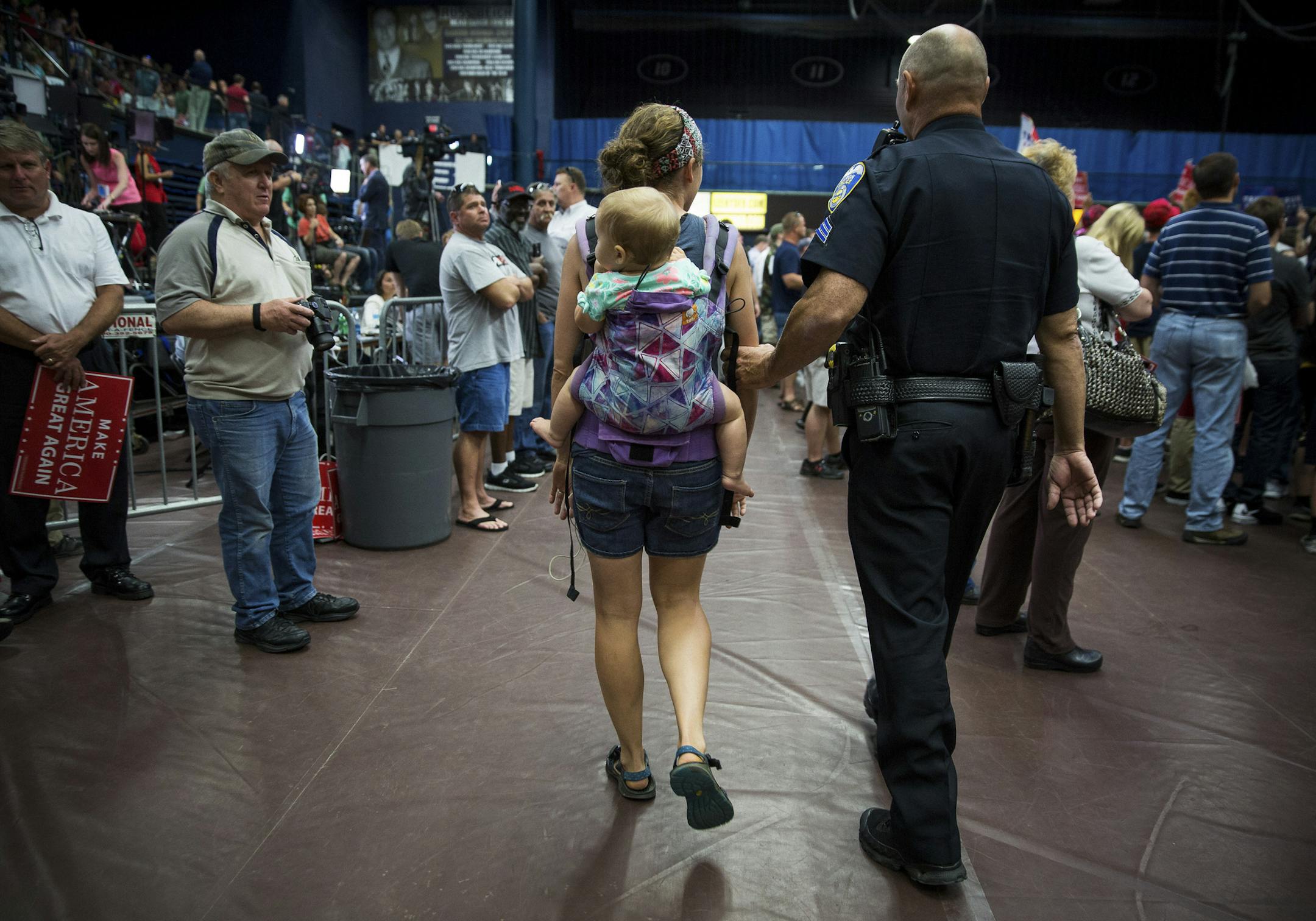 A police officer escorts a protester and her baby out of a campaign event for Donald Trump at the James A. Rhodes Arena in Akron, Ohio, Aug. 22, 2016. The protester held a hand-made sign that read "babies against racism." Trump, tempering the tone of his hard-line approach to tackling immigration reform, said earlier on Monday that he wants to come up with a plan that is “really fair” to address the millions of undocumented immigrants now in the country. (Damon Winter/The New York