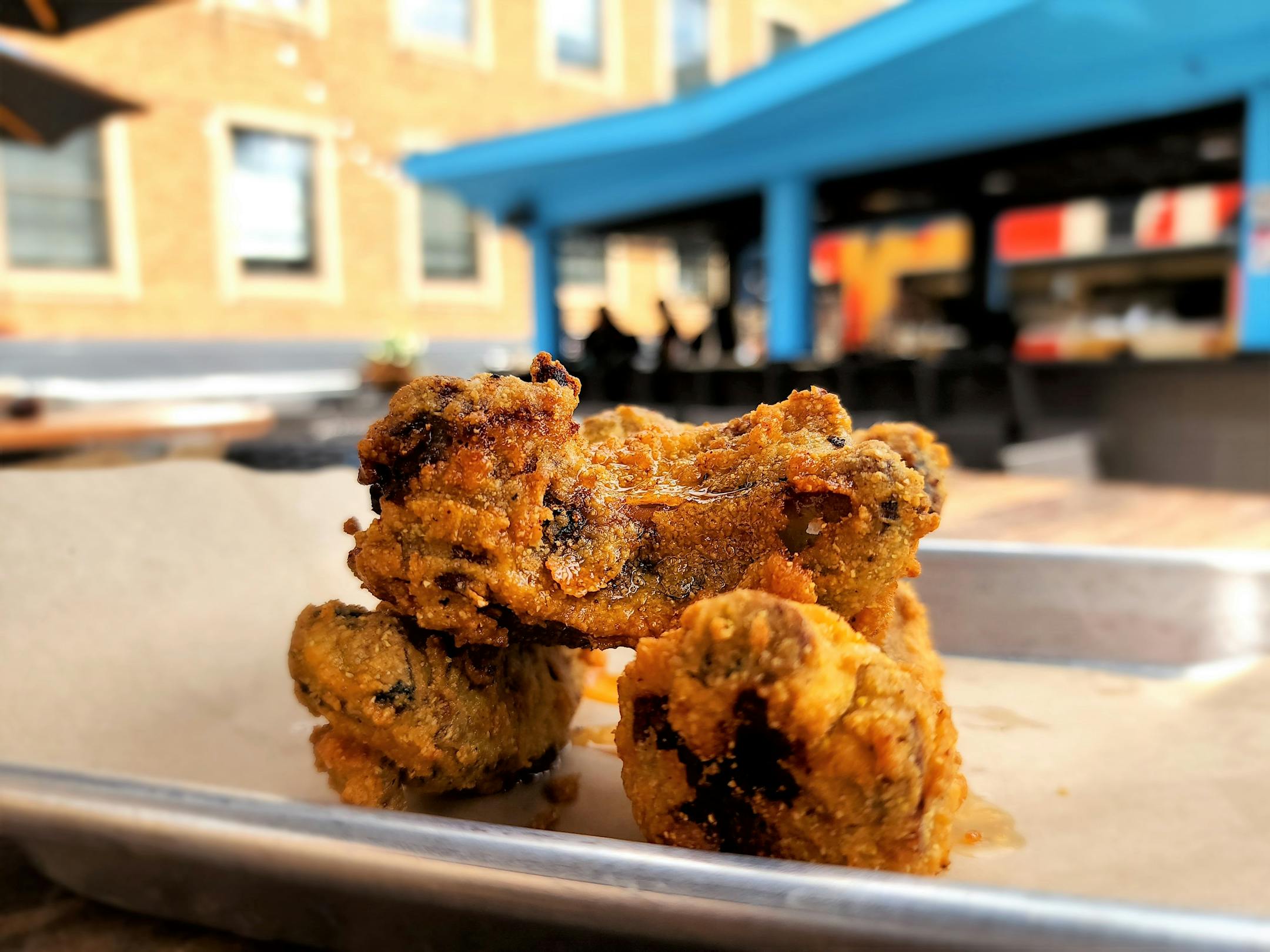 A stack of fried ribs on a tray, seen on a rooftop patio