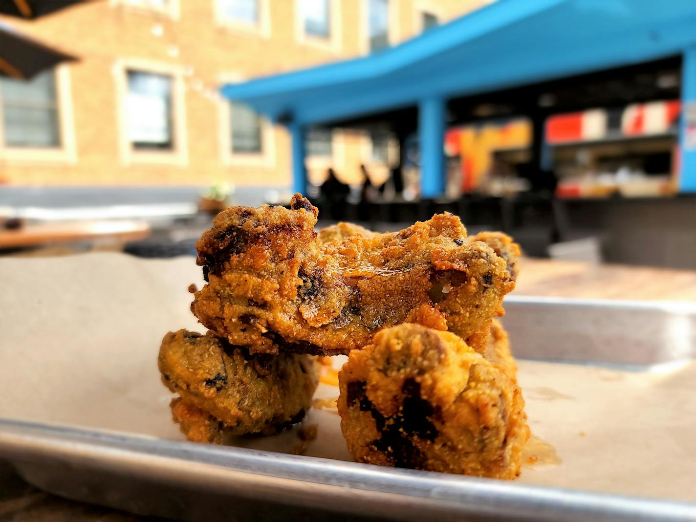 A stack of fried ribs on a tray, seen on a rooftop patio