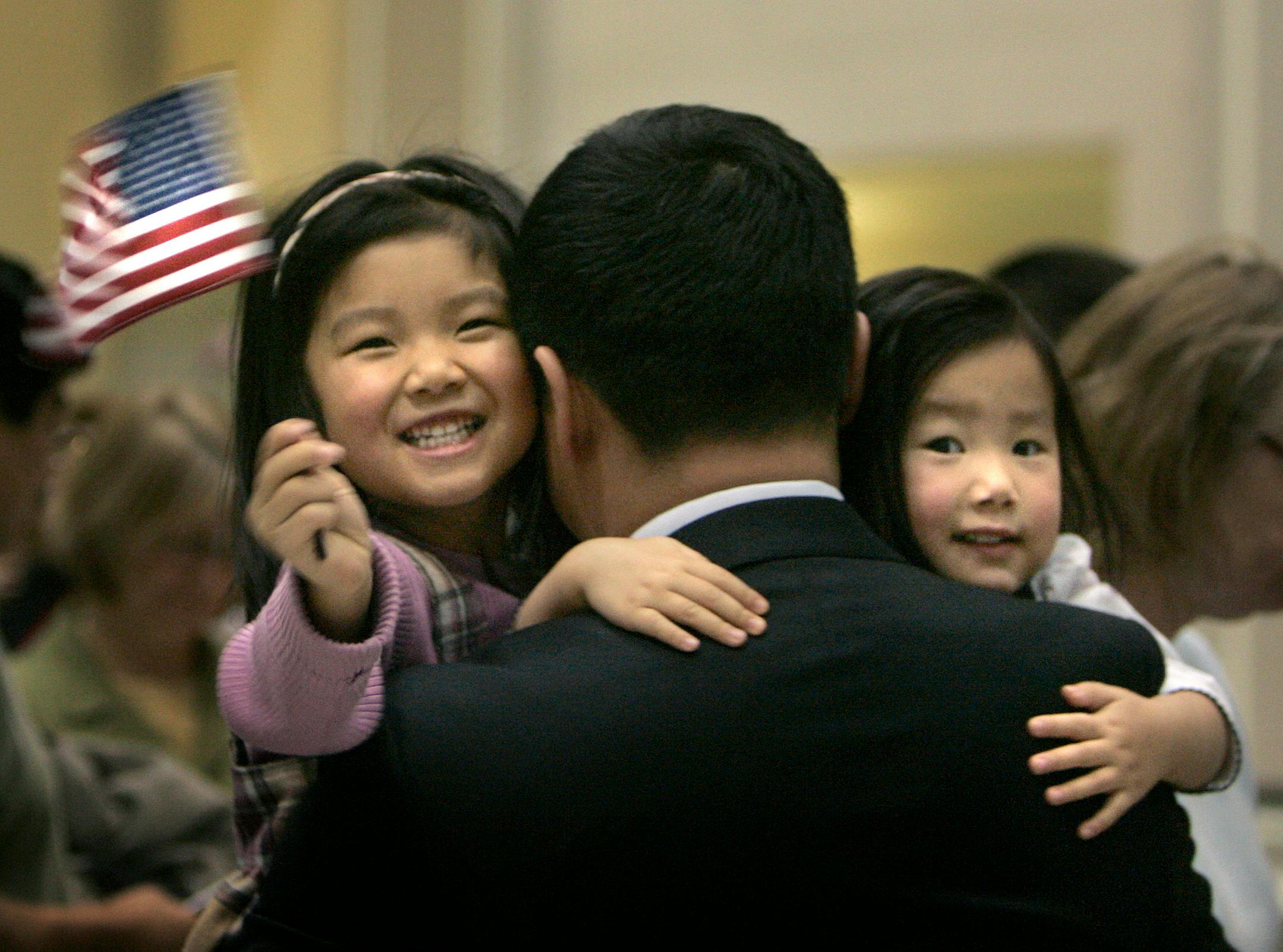 Margaret Wang, 4, waved a flag as her sister Sophia, 2, held onto their father, Ke Wang, who became a U.S. citizen in St. Paul on Wednesday. He was one of about 250 people from more than 50 countries who received their citizenship in a ceremony presided over by U.S. District Judge Donovan Frank.