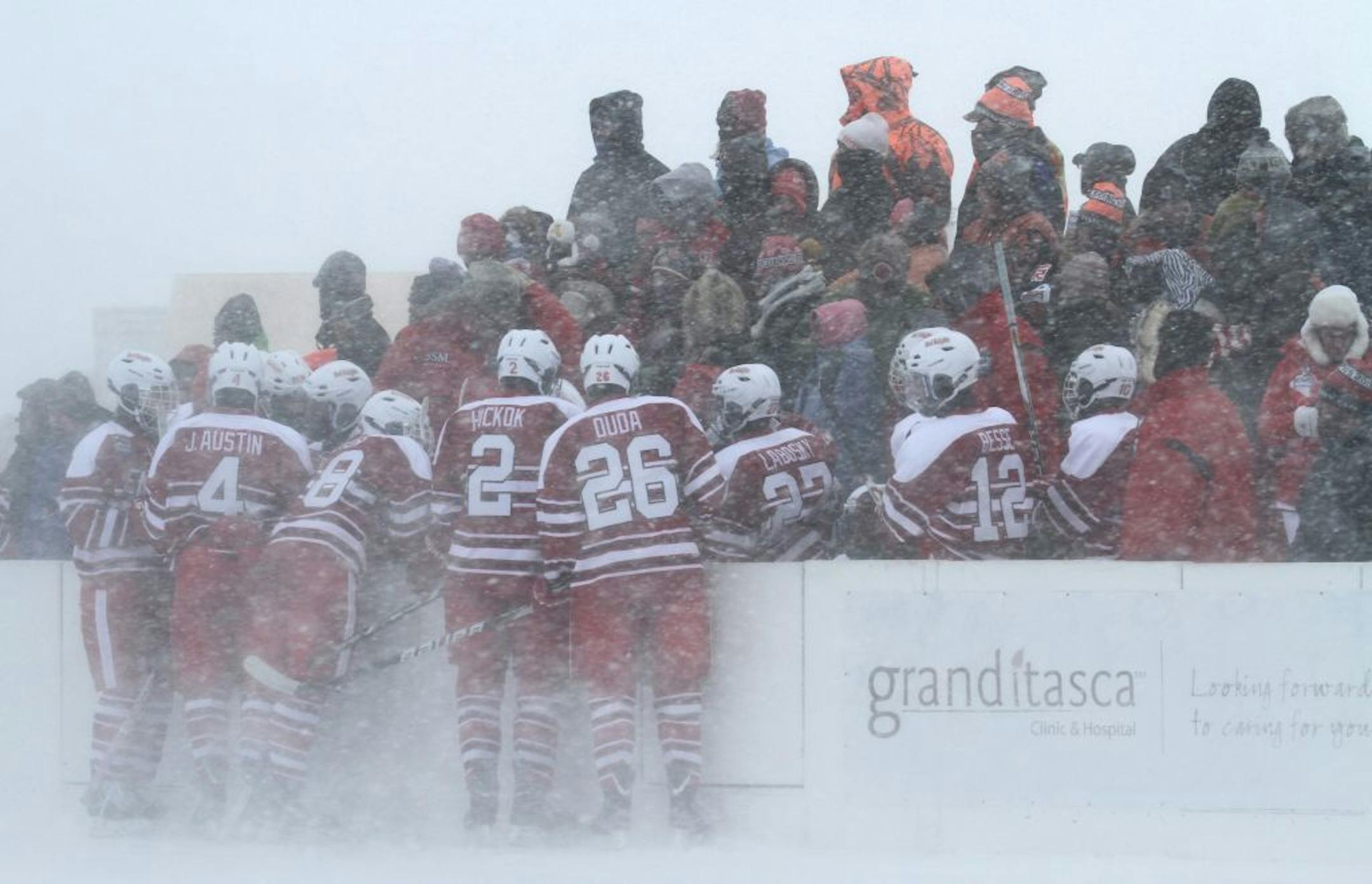 Benilde-St. Margaret's players huddled against the wind during a time-out on Hockey Day Minnesota on the shores of Lake Pokegama in Grand Rapids.
