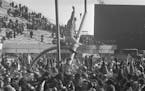 The goal posts at Metropolitan Stadium are tipped at precarious angle as happy Minnesota Vikings fans work to bring them down following the Vikings wi
