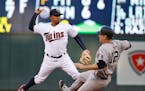 Minnesota Twins shortstop Eduardo Escobar, left, makes the throw to first to turn a double play after forcing out New York Yankees' Chase Headley (12)
