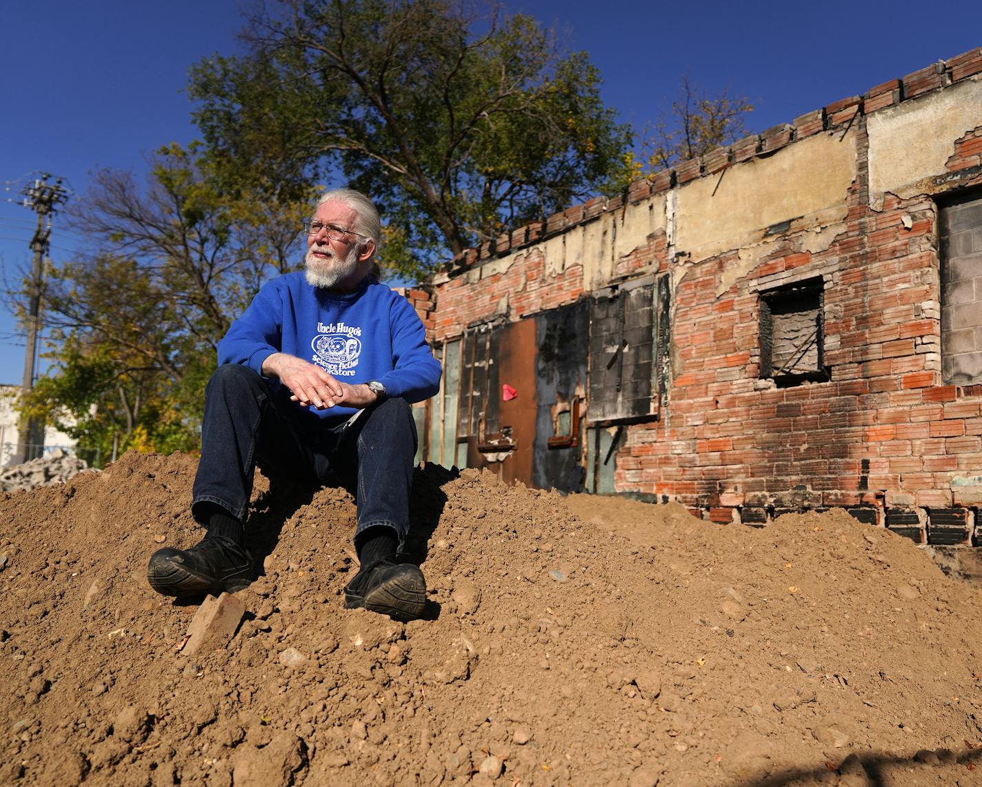 Uncle Hugo's owner Don Blyly sat for a portrait atop a pile of dirt that was once his science fiction book store on Chicago avenue before it was burned in the riots following the death of George Floyd. ] ANTHONY SOUFFLE • anthony.souffle@startribune.com Uncle Hugo's owner Don Blyly can't afford to rebuild at his current location, so he is planning to sell his riot-damaged site on Chicago avenue to his next door neighbor, dentist Dr. Ali Barbarawi, who both visited the property Thursday, Oct. 8,