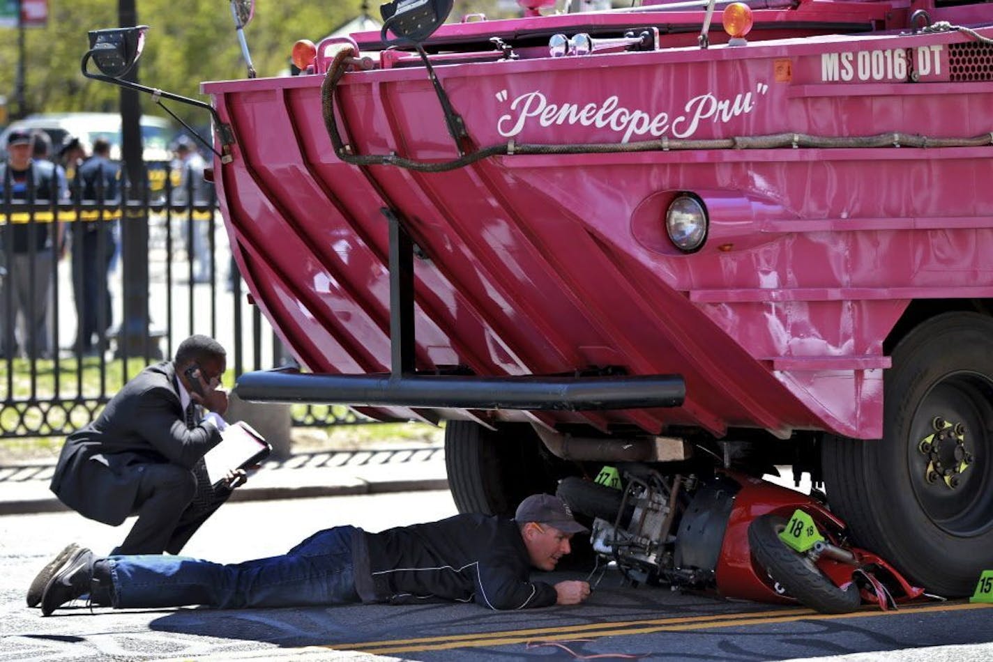 FILE - In this April 30, 2016, file photo, investigators work the scene of an accident involving a duck boat where a woman died after the scooter she was driving was struck by the amphibious sightseeing vehicle in downtown Boston. With an ability to travel by land and by sea, duck boats have long been tourist attractions for sightseers around the U.S. A spate of deadly accidents has forced safety improvements and has prompted some to call for a total ban on the vehicles.