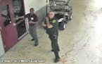 This Feb. 14, 2018 frame from security video provided by the Broward County Sheriff's Office shows deputy Scot Peterson, right, outside Marjory Stonem